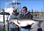 Joe Zimmer of Berlin, Maryland&#160;(left) caught this 56-pound striped bass jigging a bucktail just off the beach at Cape Hatteras. Winter 2010.
